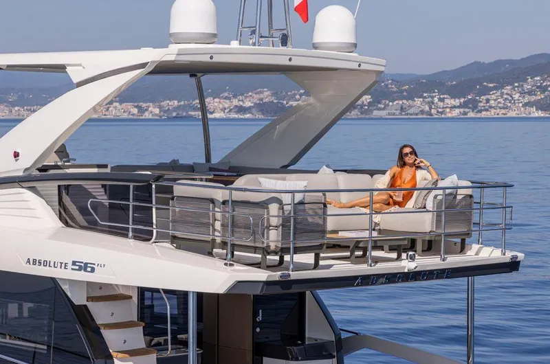 Absolute 56 Fly Yacht Photos Pics Luxury yacht Absolute 56 FLY 2025 with woman relaxing on deck, scenic coastal backdrop.