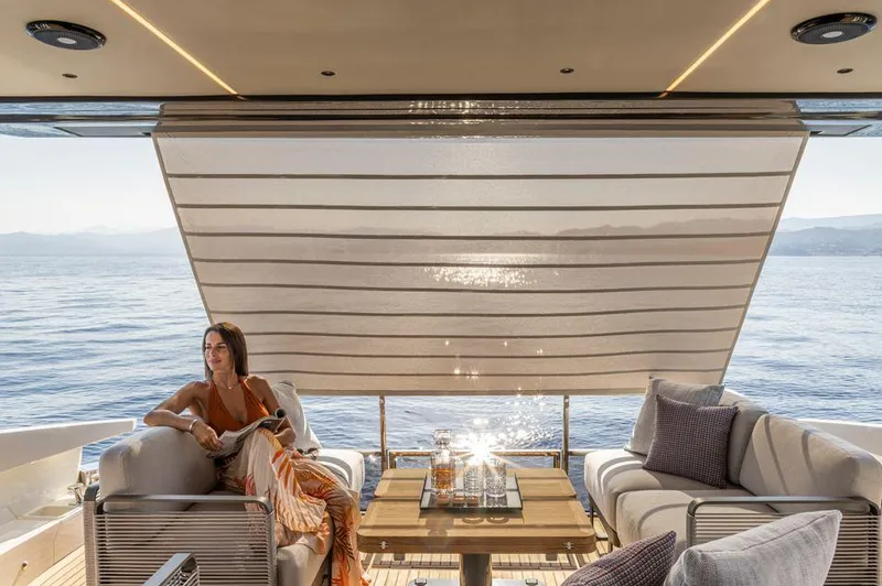 Absolute 56 Fly Yacht Photos Pics Luxury yacht Absolute 56 FLY 2025, elegant outdoor seating, ocean view, woman relaxing.