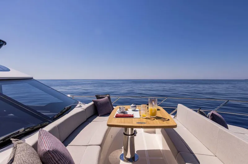 Absolute 56 Fly Yacht Photos Pics Luxury yacht Absolute 56 FLY 2025, ocean view, outdoor seating, table with drinks and snacks.