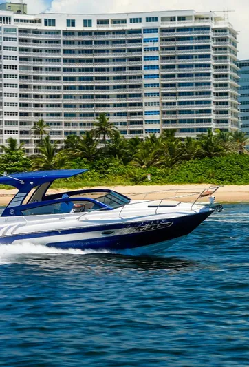 Custom Order Your 305 Today! Yacht Photos Pics 2025 Hanover 305 Outboard cruising near a beachfront with modern high-rise buildings.