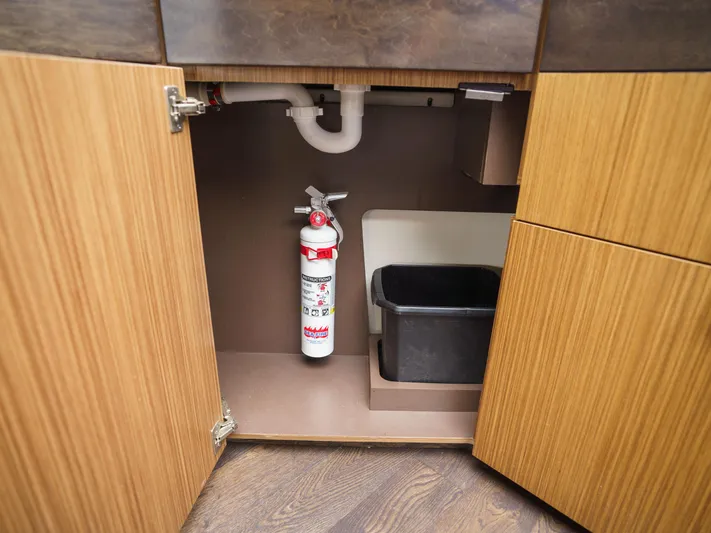Lakehouse Yacht Photos Pics Under-sink storage with fire extinguisher and bin on 2016 Sea Ray L590 yacht.