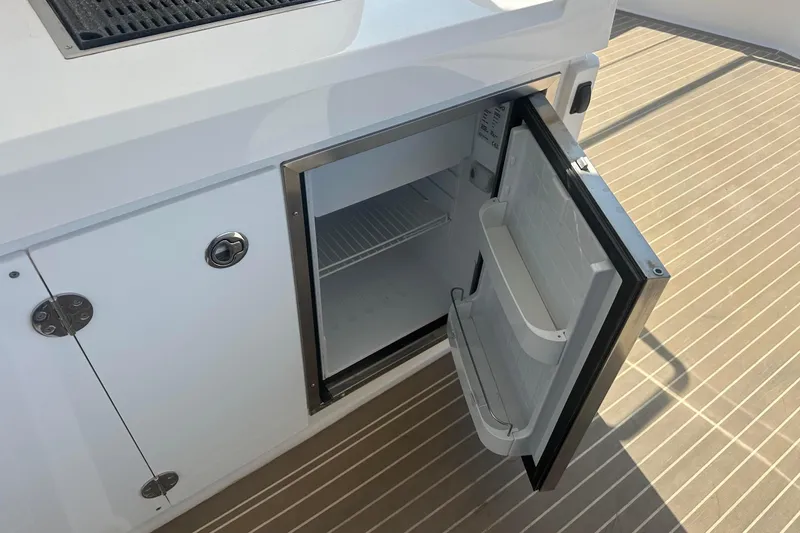 Hamlet Yacht Photos Pics Open mini fridge on Leopard 46PC yacht, 2023 model, with white cabinetry and wooden deck.