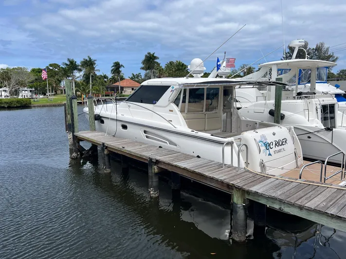 Cc Rider Yacht Photos Pics 2004 Tiara Yachts 4400 Sovran docked by a wooden pier, under a partly cloudy sky.