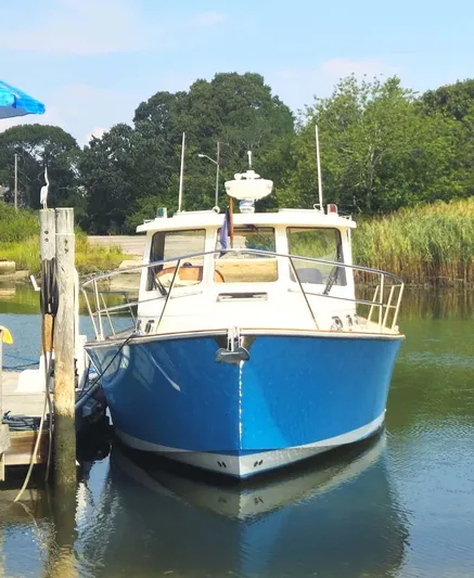 Odyssey III Yacht Photos Pics Blue 2008 Legacy 32 boat docked in a serene, tree-lined marina.