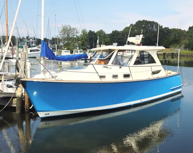 Odyssey III Yacht Photos Pics Blue 2008 Legacy 32 boat docked in a marina, surrounded by trees and other boats.