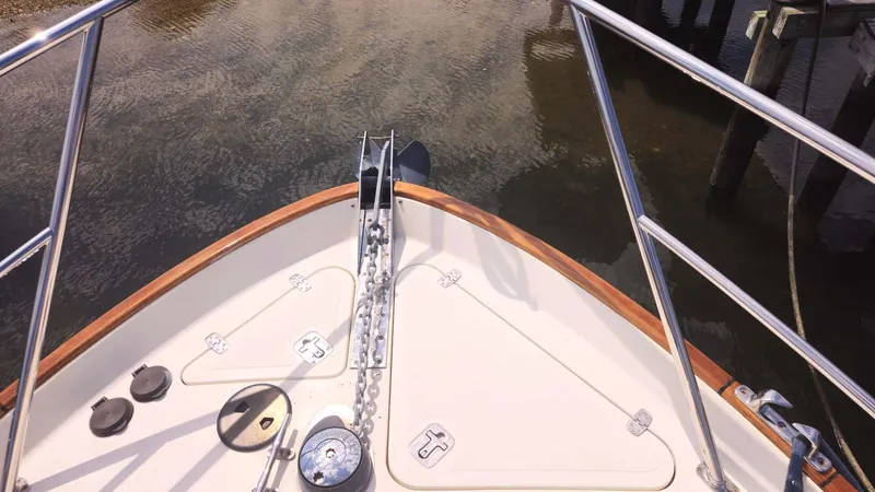 Odyssey III Yacht Photos Pics Bow of a 2008 Legacy 32 boat with anchor and railing in calm water.