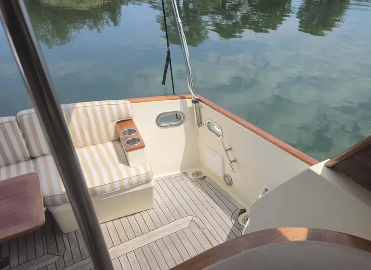 Odyssey III Yacht Photos Pics 2008 Legacy 32 boat deck with striped seating and calm water reflection.