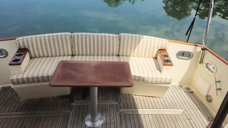 Odyssey III Yacht Photos Pics Elegant seating area on 2008 Legacy 32 boat with striped cushions and wooden table.