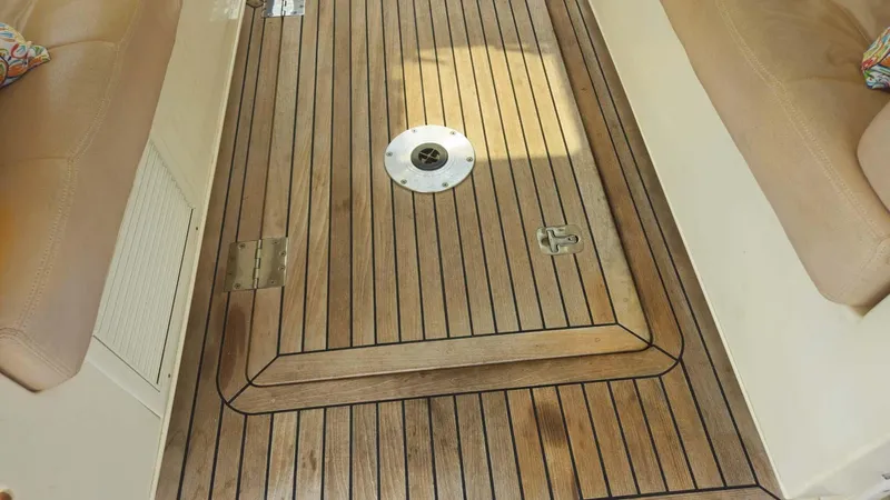 Odyssey III Yacht Photos Pics Teak deck of 2008 Legacy 32 boat, featuring a central hatch and beige seating.