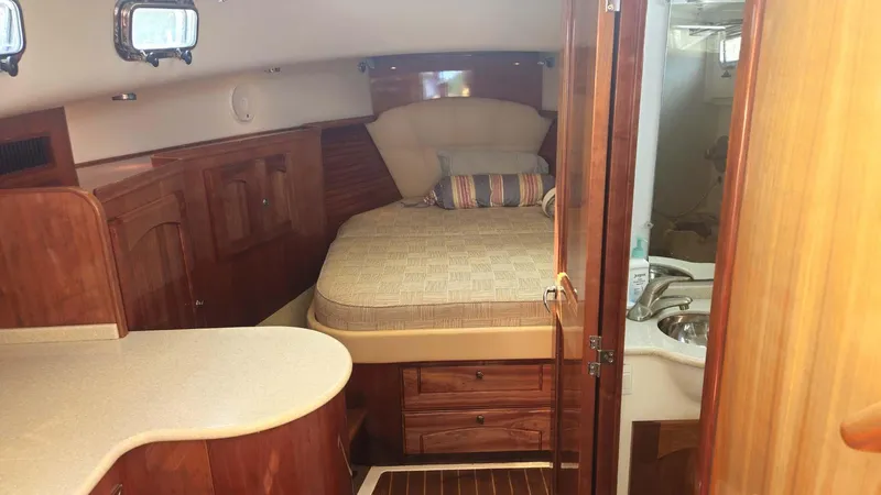 Odyssey III Yacht Photos Pics 2008 Legacy 32 yacht interior with cozy bed, wooden cabinetry, and compact bathroom.