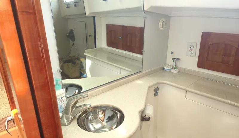 Odyssey III Yacht Photos Pics Compact bathroom in 2008 Legacy 32 boat with sink, mirror, and storage cabinets.