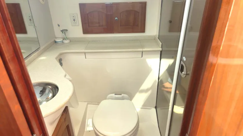 Odyssey III Yacht Photos Pics Compact bathroom in 2008 Legacy 32 boat with toilet, sink, and wooden cabinets.