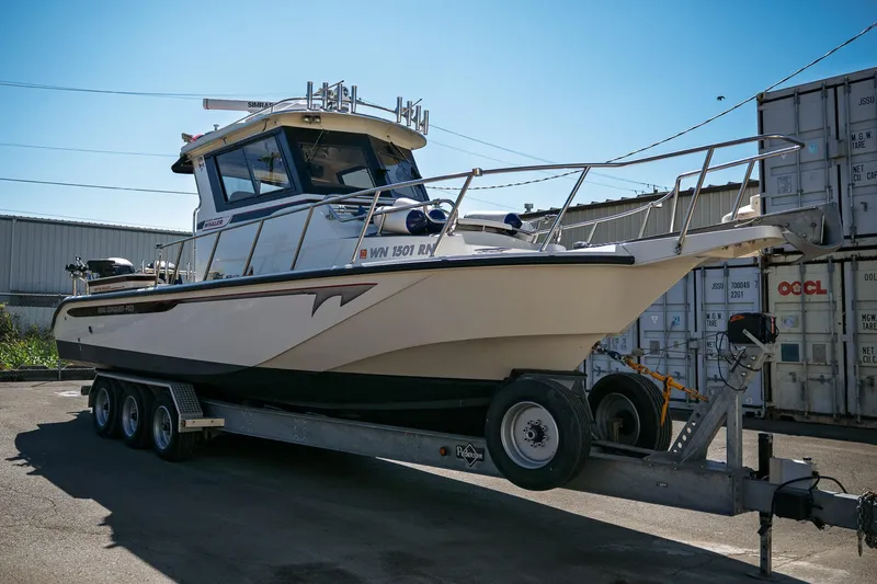 Yacht Photos Pics 1990 Boston Whaler 31 Offshore Custom Conquest on trailer, parked near shipping containers.