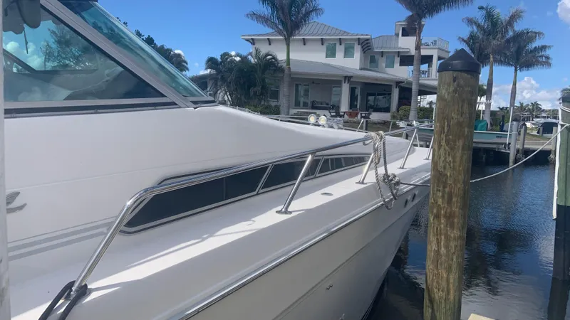 Amusement Yacht Photos Pics 1994 Sea Ray 500 Sundancer yacht docked near waterfront home with palm trees.
