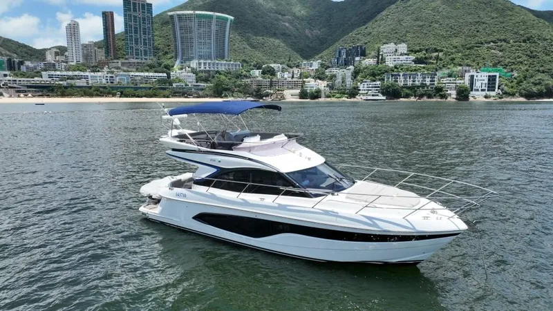  Yacht Photos Pics Luxury 2020 Princess F45 yacht cruising near scenic coastline and modern buildings.