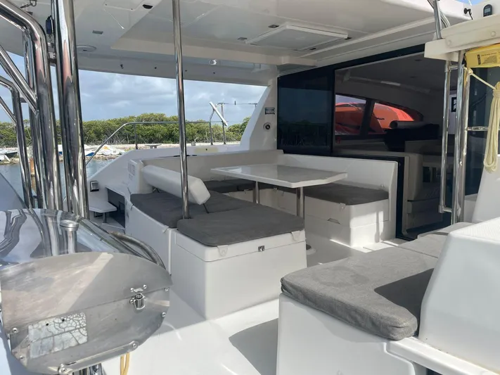 Morning Star Yacht Photos Pics 2021 Leopard 40 catamaran with outdoor seating and dining area, docked by lush greenery.