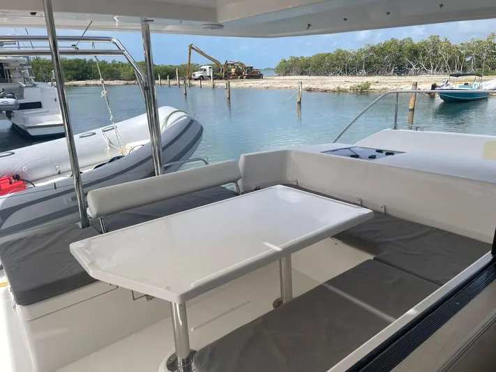 Morning Star Yacht Photos Pics Leopard 40 catamaran's outdoor seating area with table, docked near a serene waterfront.