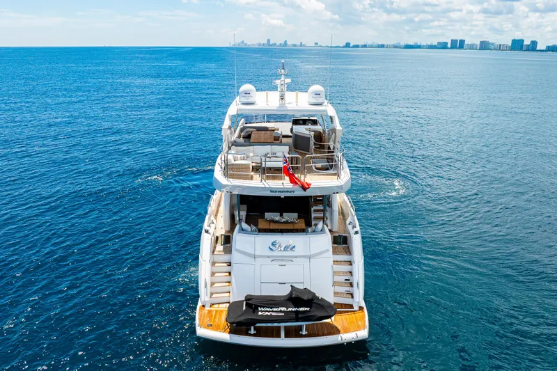  Yacht Photos Pics 2021 Sunseeker 76 Yacht on open sea, rear view, with city skyline in background.