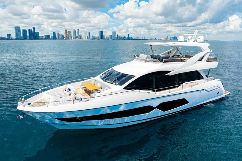  Yacht Photos Pics 2021 Sunseeker 76 Yacht cruising on blue ocean with city skyline in background.