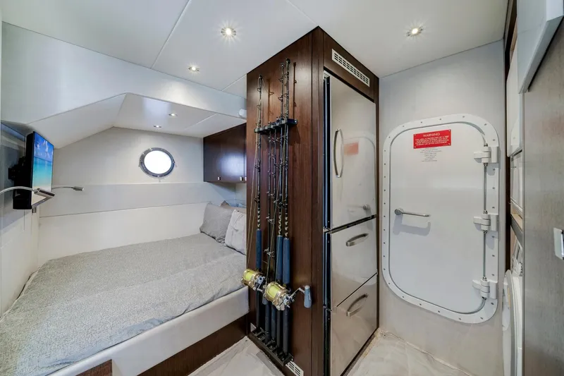 Yacht Photos Pics Interior cabin of 2021 Sunseeker 76 Yacht with bed, porthole, and fishing rods.