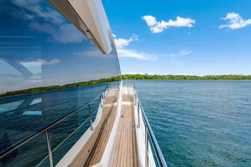  Yacht Photos Pics 2021 Sunseeker 76 Yacht cruising on a serene lake under a clear blue sky.
