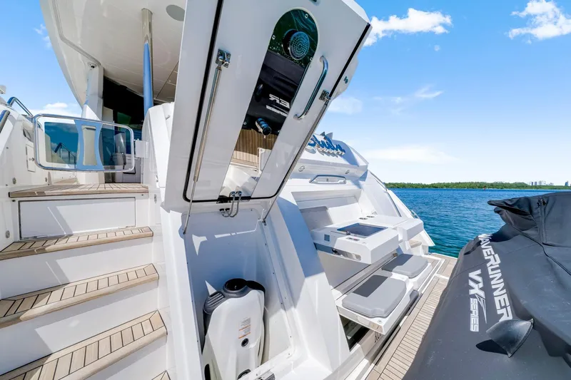  Yacht Photos Pics Sunseeker 76 Yacht 2021 with open storage, steps, and jet ski on deck by the water.