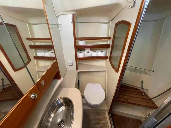 Sapphire Seas Yacht Photos Pics Bathroom interior of 2006 Hunter 45 Center Cockpit yacht with sink, toilet, and wooden shelves.