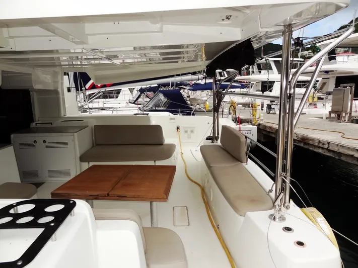 Shamwari Yacht Photos Pics Spacious deck of 2020 Lagoon 46 catamaran with seating and table, docked at marina.