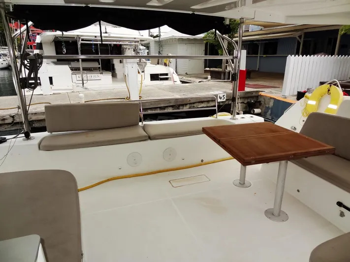 Shamwari Yacht Photos Pics Outdoor seating area on a 2020 Lagoon 46 catamaran, featuring a wooden table and cushioned benches.