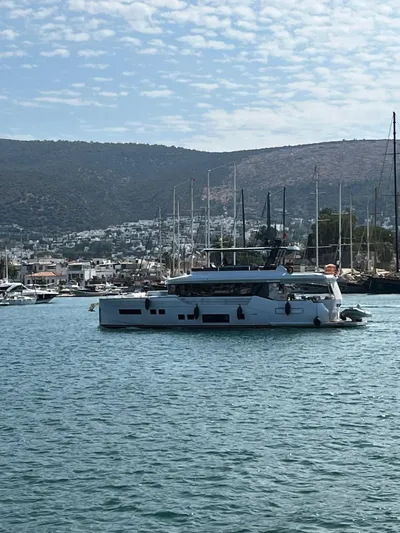  Yacht Photos Pics Luxury Sirena 68 yacht, 2023 model, cruising in a scenic harbor with hills in the background.