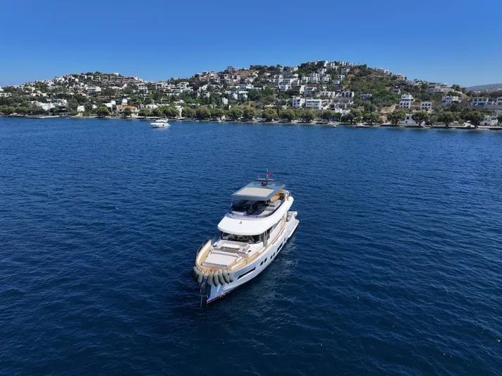  Yacht Photos Pics 2023 Sirena 68 yacht cruising on blue waters near a scenic coastal town.