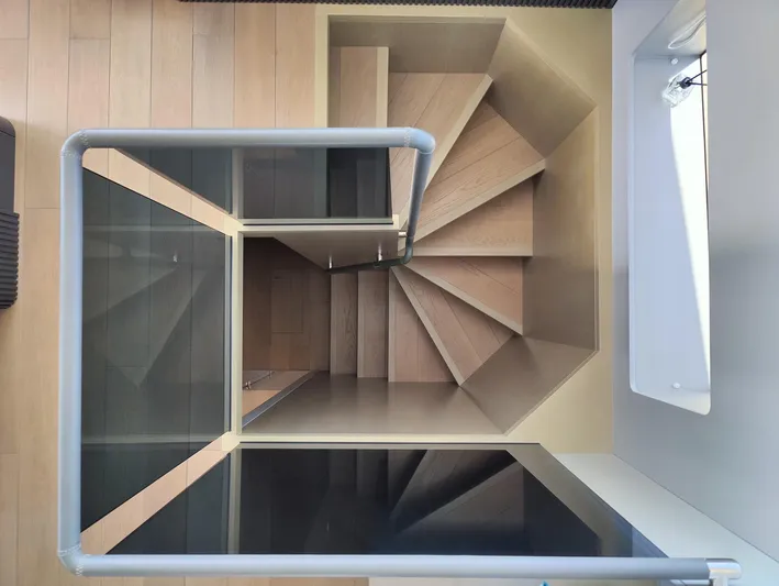  Yacht Photos Pics Spiral staircase in a 2023 Sirena 68 yacht, featuring modern wood and glass design.