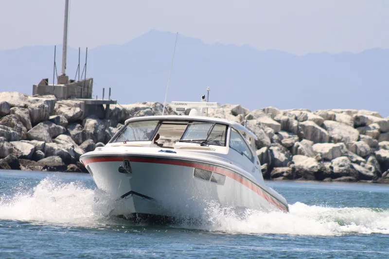 Flawless Seas Yacht Photos Pics 2019 Pursuit DC 365 Dual Console boat navigating near rocky shoreline.