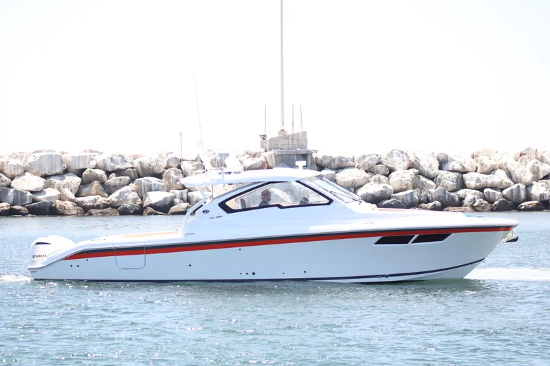 Flawless Seas Yacht Photos Pics 2019 Pursuit DC 365 Dual Console boat cruising near rocky shoreline.