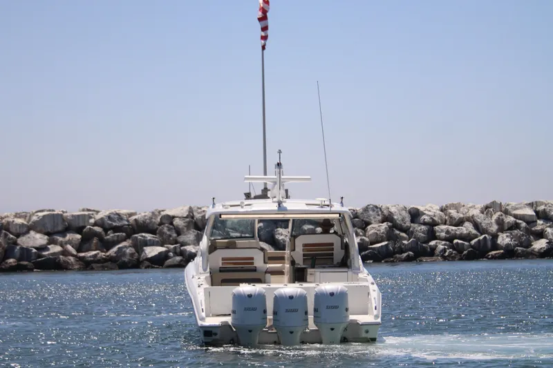 Flawless Seas Yacht Photos Pics 2019 Pursuit DC 365 Dual Console boat cruising near rocky shoreline.