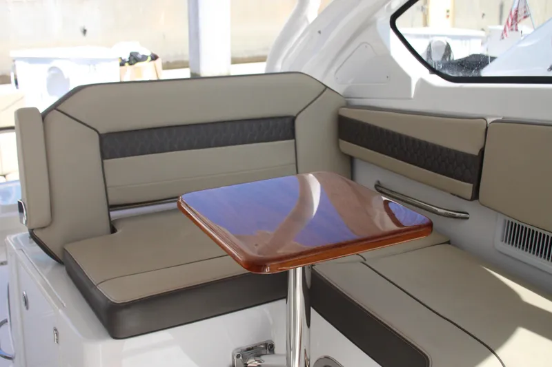 Flawless Seas Yacht Photos Pics 2019 Pursuit DC 365 Dual Console interior with cushioned seating and wooden table.