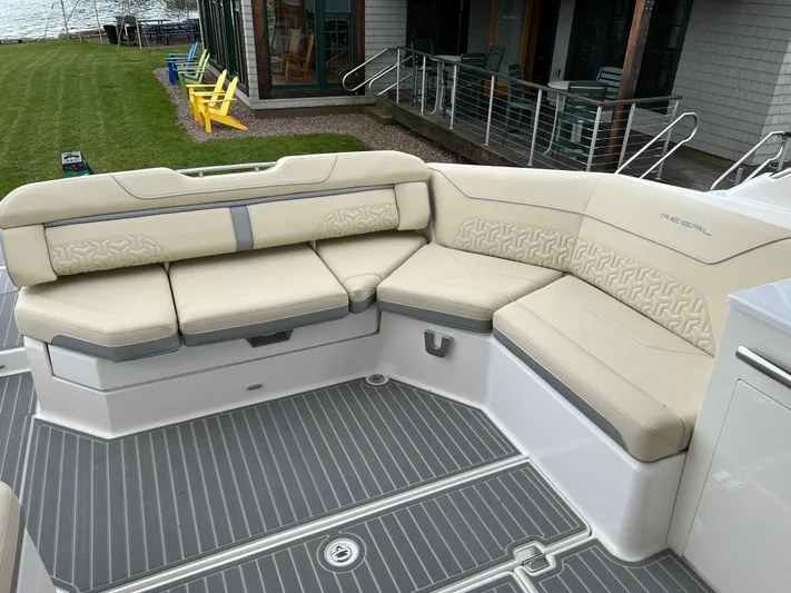  Yacht Photos Pics 2022 Regal LS36 boat with beige seating and gray flooring, docked near a lawn.