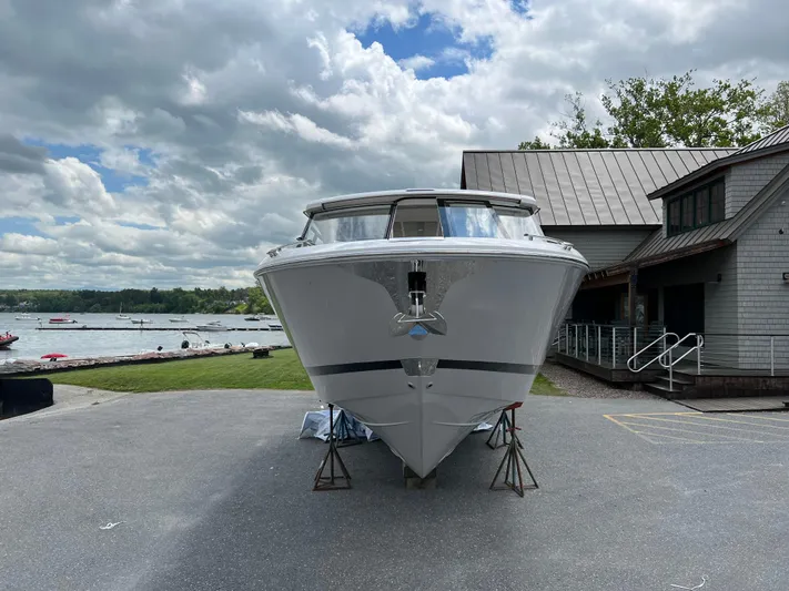  Yacht Photos Pics 2022 Regal LS36 boat on land near a lake and building under cloudy sky.