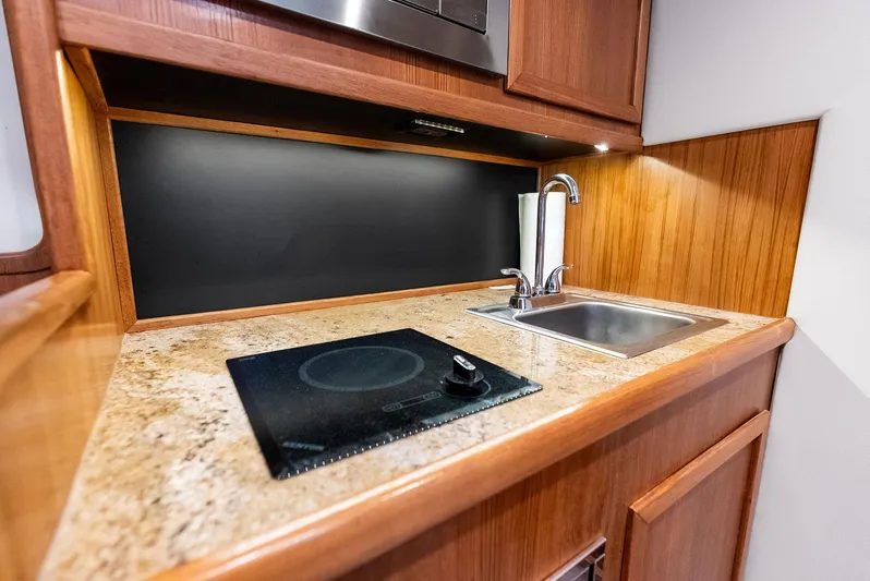 Let's Go Yacht Photos Pics Compact kitchen area in a 2018 Custom Carolina 35 Express boat with sink and stovetop.