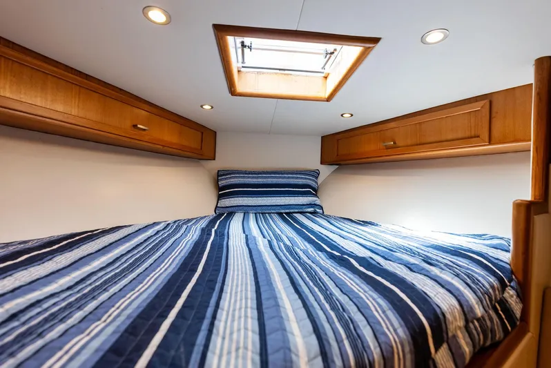 Let's Go Yacht Photos Pics Cozy cabin interior of 2018 Custom Carolina 35 Express with striped bedding and wooden cabinets.