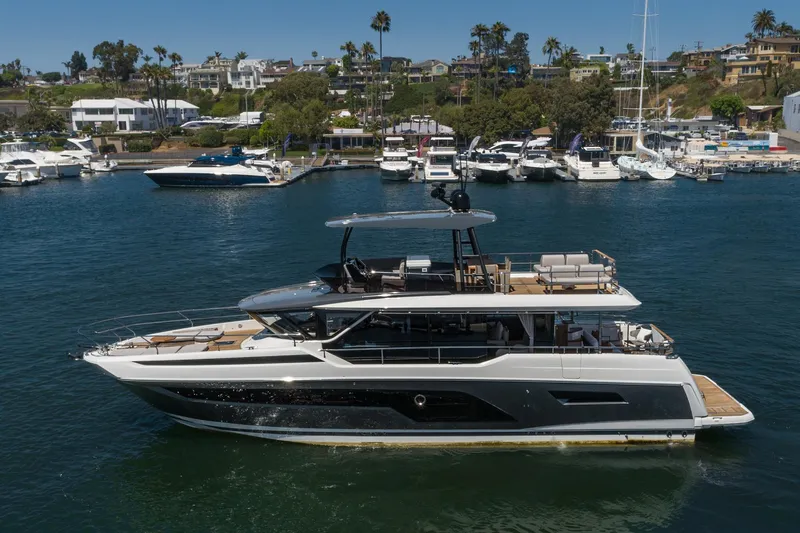  Yacht Photos Pics 2024 Prestige X60 yacht cruising in a marina with luxury boats and waterfront homes.