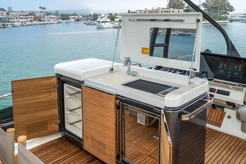  Yacht Photos Pics Outdoor kitchen on 2024 Prestige X60 yacht with grill and storage, overlooking marina.