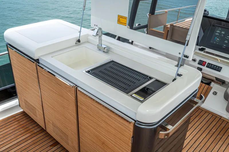  Yacht Photos Pics Outdoor kitchen on 2024 Prestige X60 yacht with sink and grill, overlooking the ocean.