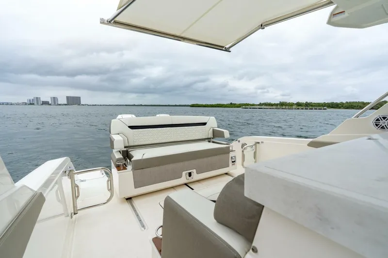  Yacht Photos Pics 2024 Tiara Sport 34 LS boat interior with seating, overlooking calm waters and cloudy sky.