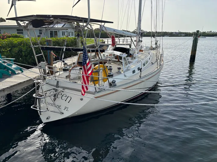 Colleen Yacht Photos Pics 1984 Cambria 44/46 sailboat docked, displaying an American flag, calm water background.