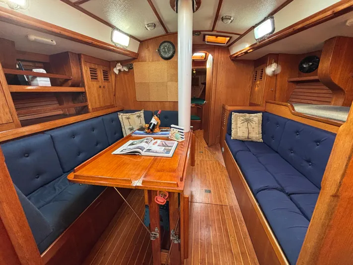 Colleen Yacht Photos Pics Cozy 1984 Cambria 44/46 yacht interior with wooden furnishings and blue cushioned seating.