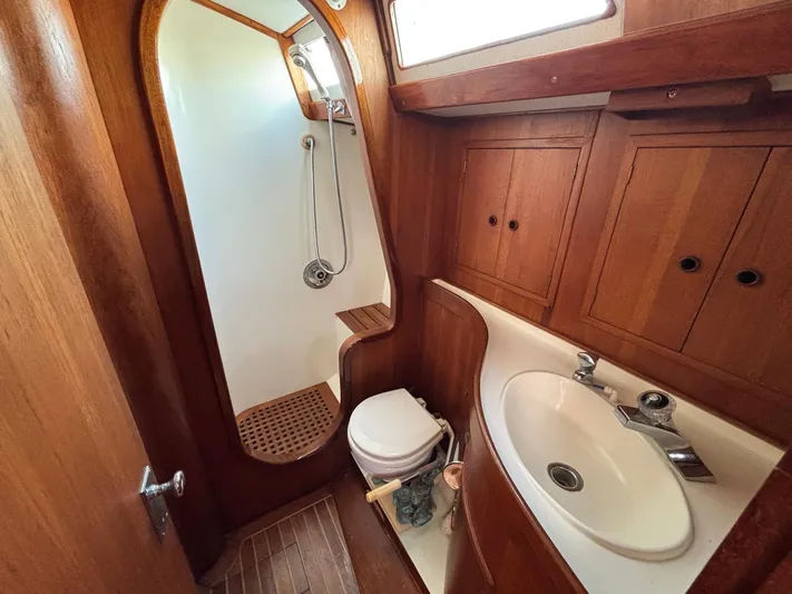 Colleen Yacht Photos Pics 1984 Cambria 44/46 yacht bathroom with wooden cabinetry, sink, and shower area.