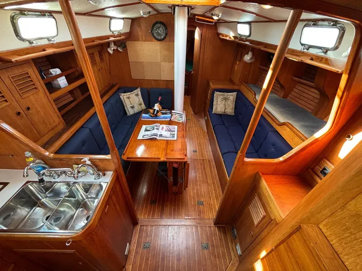 Colleen Yacht Photos Pics Interior of 1984 Cambria 44/46 sailboat with wooden finishes and blue seating.