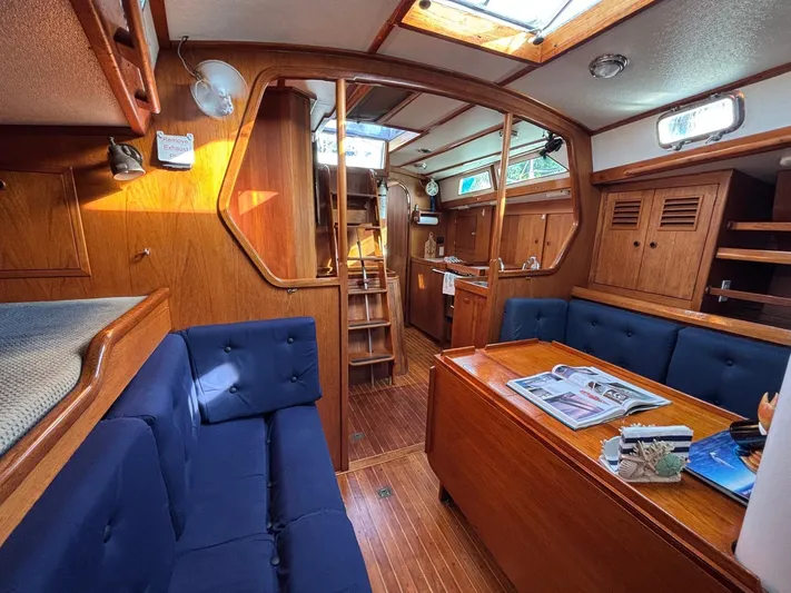 Colleen Yacht Photos Pics Interior of 1984 Cambria 44/46 sailboat with wooden furnishings and blue seating.