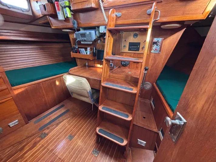 Colleen Yacht Photos Pics 1984 Cambria 44/46 yacht interior with wooden finish, navigation equipment, and green seating.